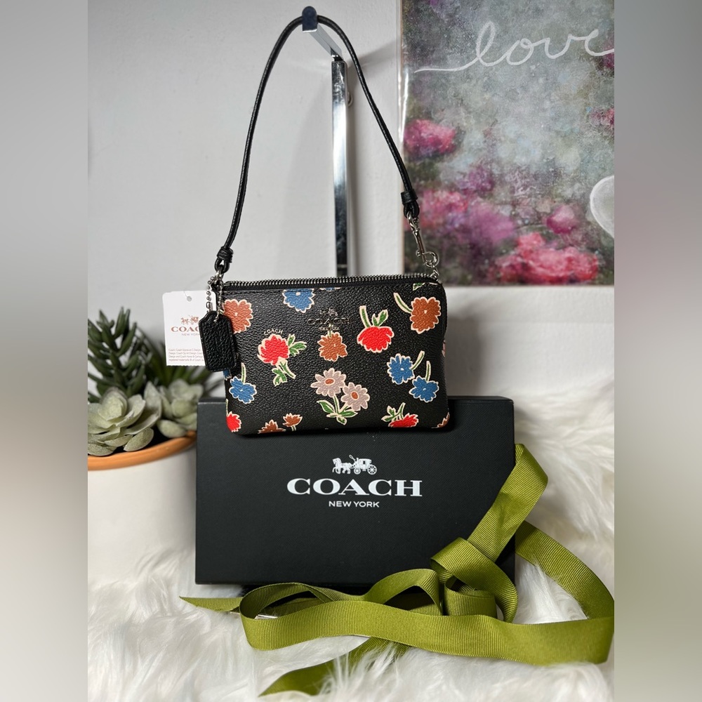 New with tag Coach wristlet with multi color daisy print.